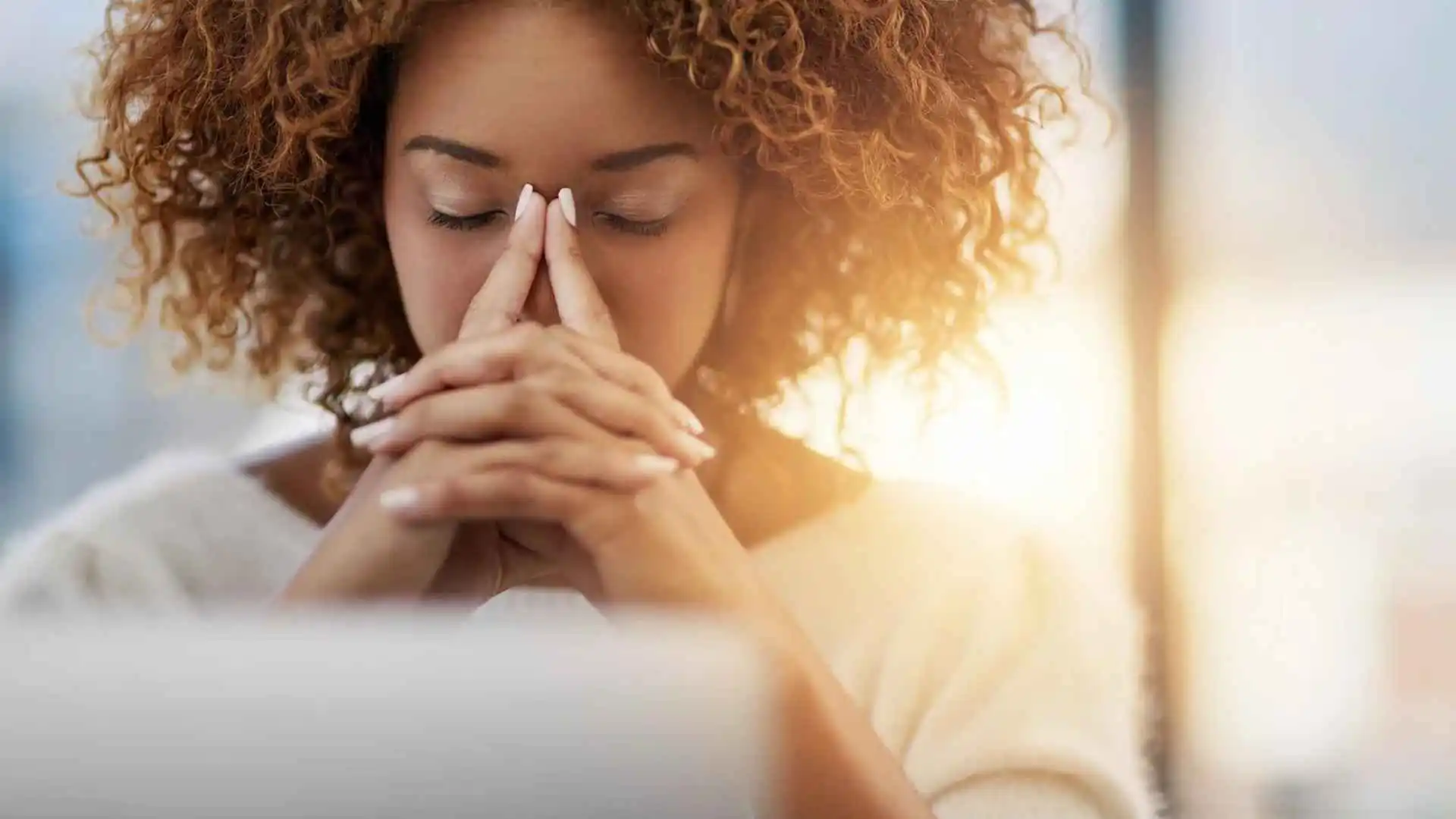 A woman behind a laptop looking like she's meditating