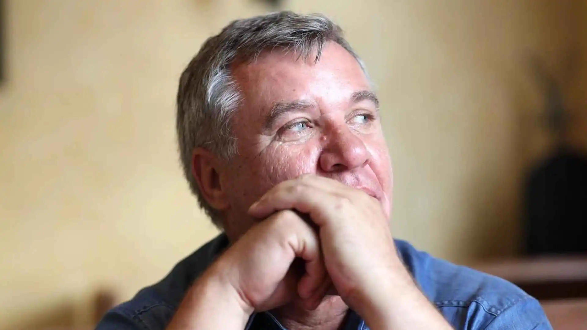 A man looking to the side with his arms in front of his mouth