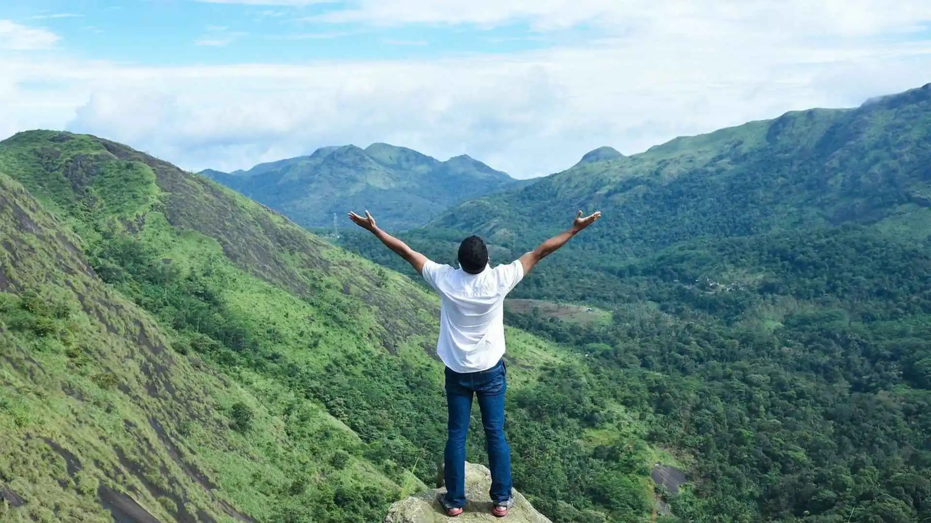 A person standing on the top of a hill looking out in triumph