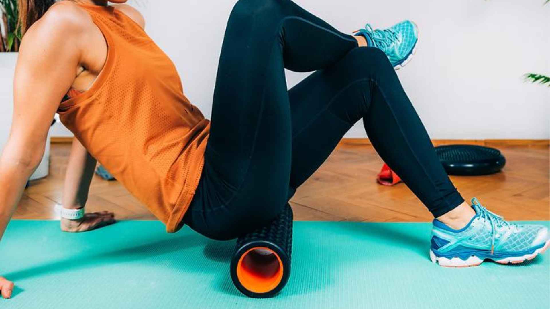 A woman in exercise clothing using a foam roller